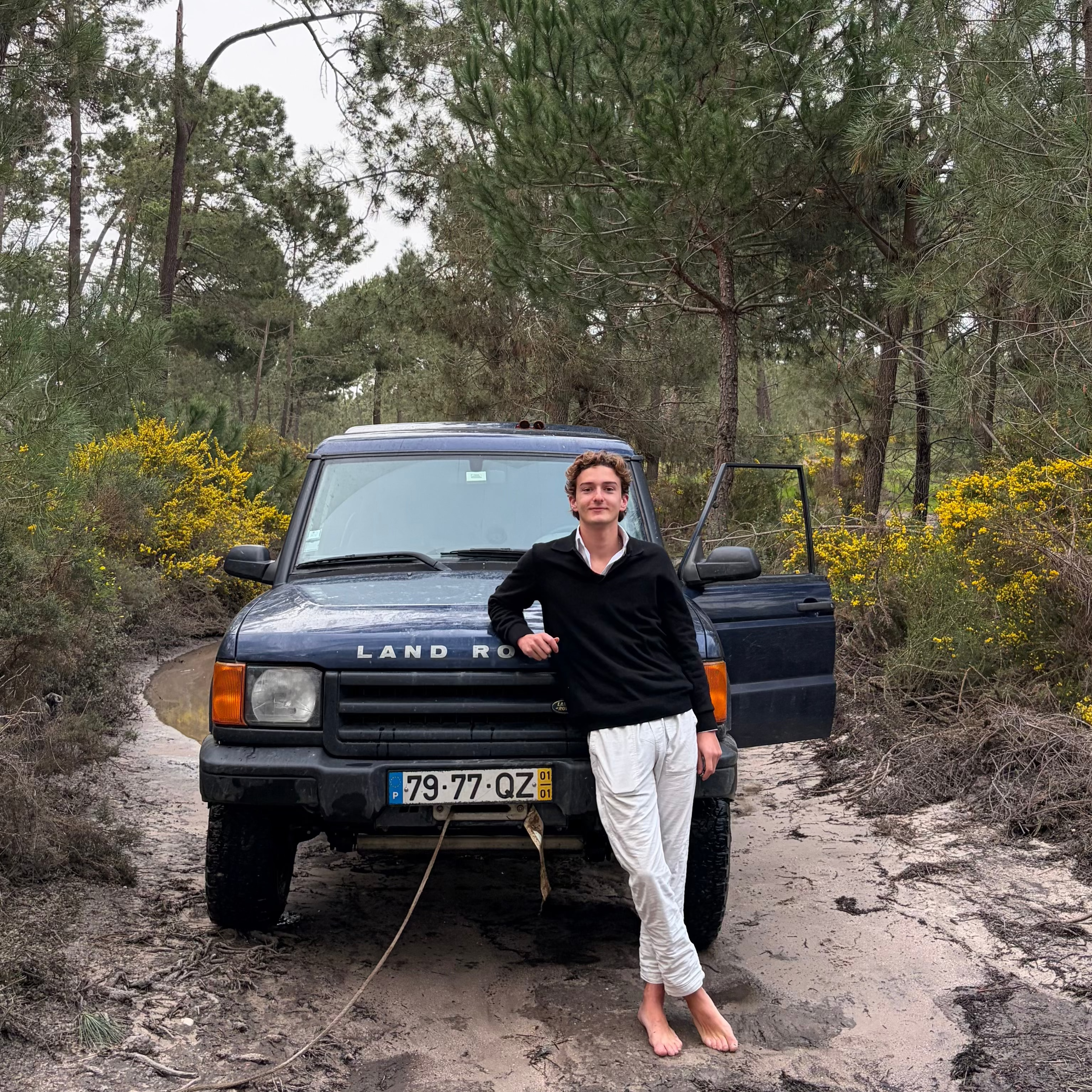 Person standing next to a Land Rover in a forested area, wearing the cashmere pullover