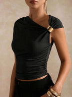 Black top with gold accents worn by a model against a beige background